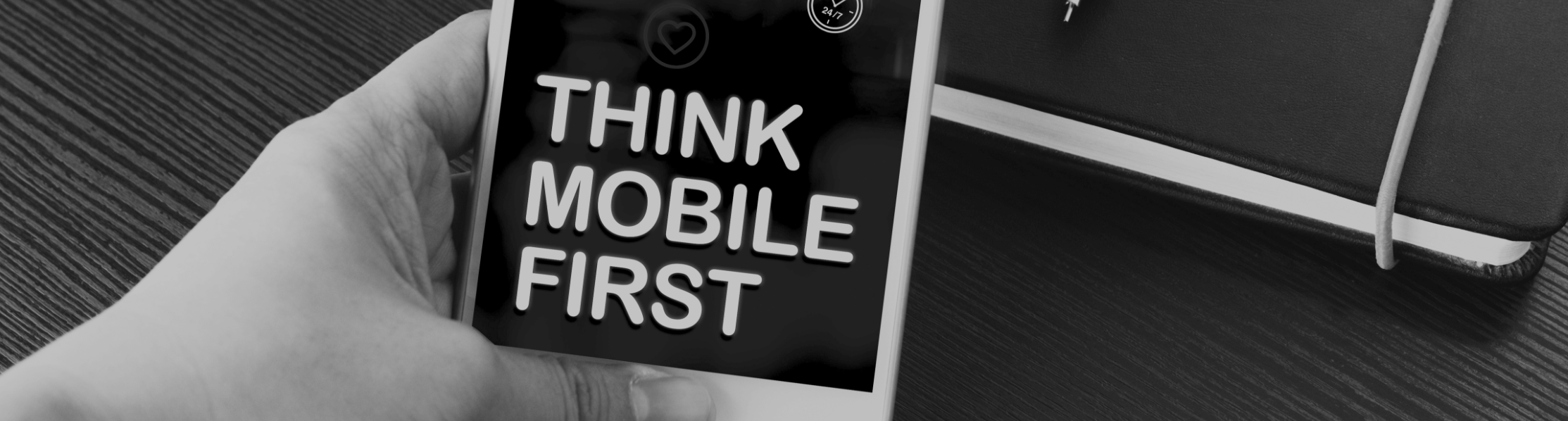 Image of a hand holding a mobile phone with the words "Think mobile first" on the screen