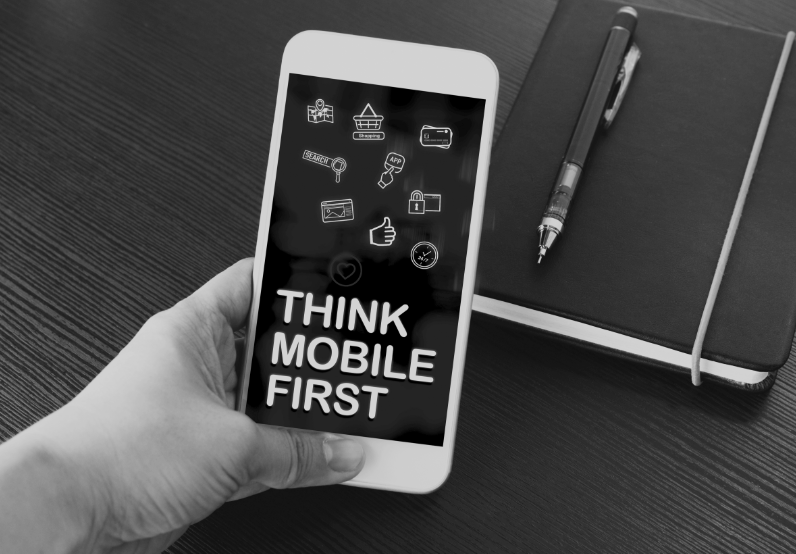 Image of a hand holding a mobile phone with the words "Think mobile first" on the screen