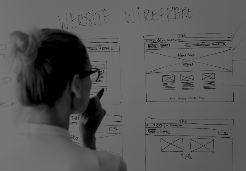 Image of a woman working on a whiteboard for website wireframes